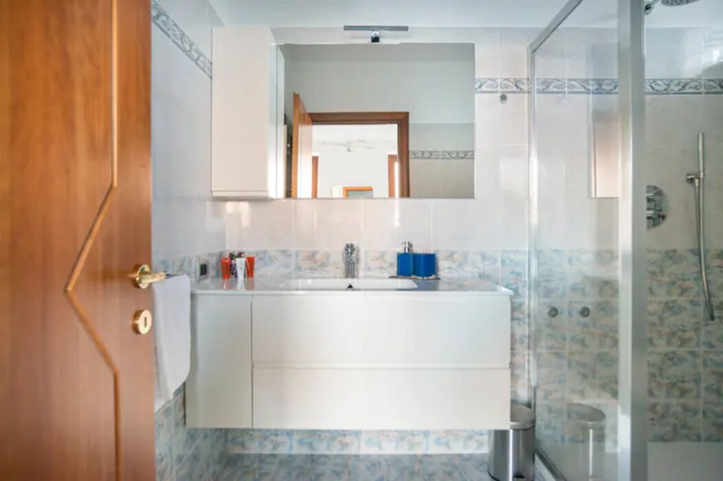 Une salle de bain avec un lavabo blanc, un miroir et une douche.