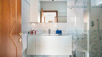 Une salle de bain avec un lavabo blanc, un miroir et une douche.