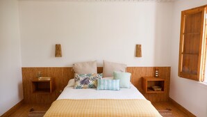 Ein Schlafzimmer mit einem Bett, zwei Nachttischen, einem Fenster und einem Holz-Kopfteil.