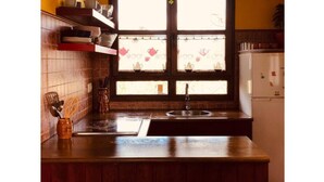 A kitchen with a wooden countertop, a stainless steel sink, and a window with a tea-themed curtain. - Holidays in Asturias (Asturias)