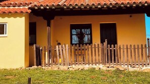 A yellow building with a tiled roof, a wooden fence, and a chimney. - Holidays in Asturias (Asturias)
