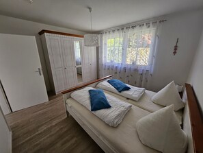 Ein Schlafzimmer mit zwei Betten, einem Kleiderschrank und einem Fenster mit Vorhängen.