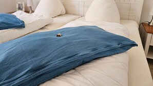 Un lit double avec une tête de lit en bois, une literie blanche et un plaid bleu.