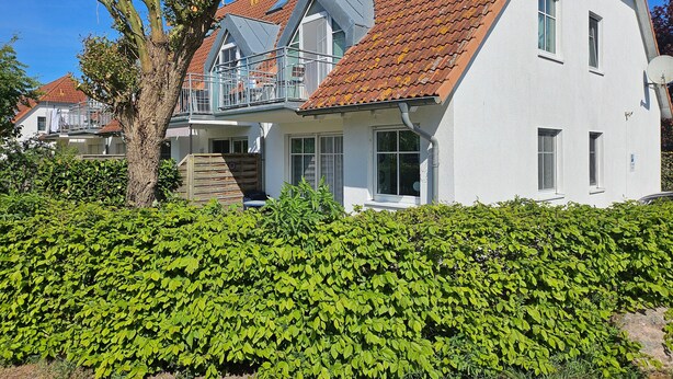 Une maison à deux étages, avec un toit recouvert de tuiles rouges, des murs extérieurs blancs et un balcon doté d’une balustrade en métal.