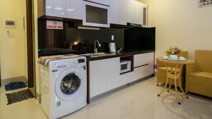 Une cuisine compacte équipée d’un lave-linge, d’un four à micro-ondes et d’un coin repas avec des meubles en osier.