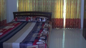 A bedroom with a bed, curtains, and a nightstand. - Furnished Flat In Block C Bashundhara RA (Dhaka)