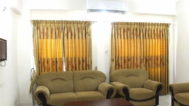 A living room with a sofa, armchair, and a wooden coffee table. - Furnished Flat In Block C Bashundhara RA (Dhaka)