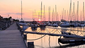 Un port de plaisance avec des bateaux amarrés, une promenade en bois et un coucher de soleil en arrière-plan.