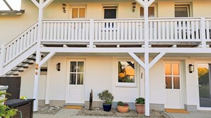 Un bâtiment à deux étages doté d’un balcon, d’un escalier et d’une porte avec une fenêtre.