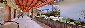 Un espacio al aire libre techado con paredes de piedra, suelo de baldosas y mobiliario para exteriores.