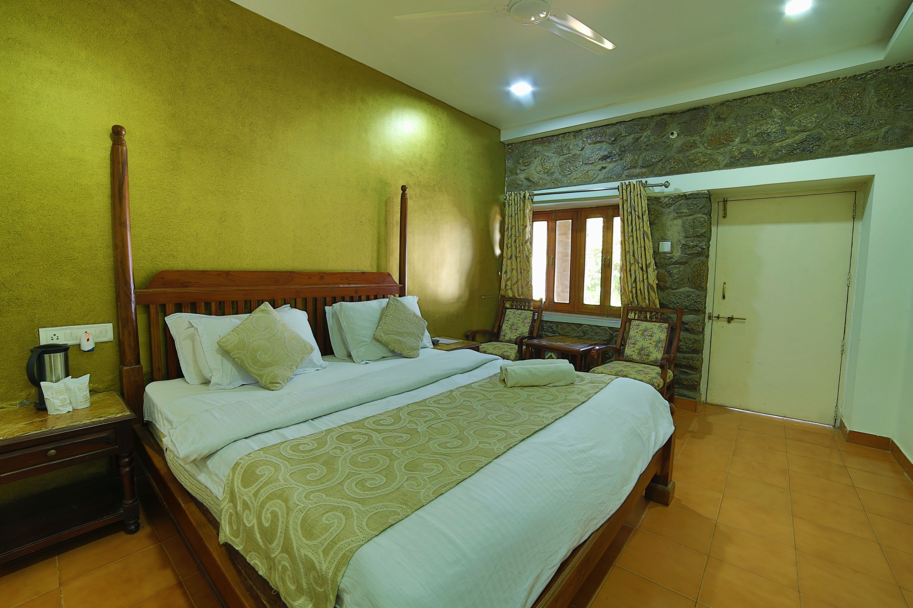 A well-lit bedroom with a large bed, wooden headboard, and a nightstand with a lamp.