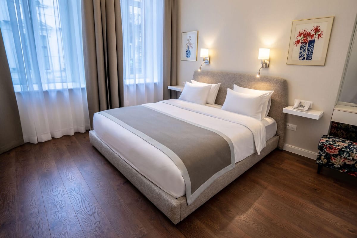 Une chambre d’hôtel avec un grand lit, une table de chevet avec une lampe et un téléphone.