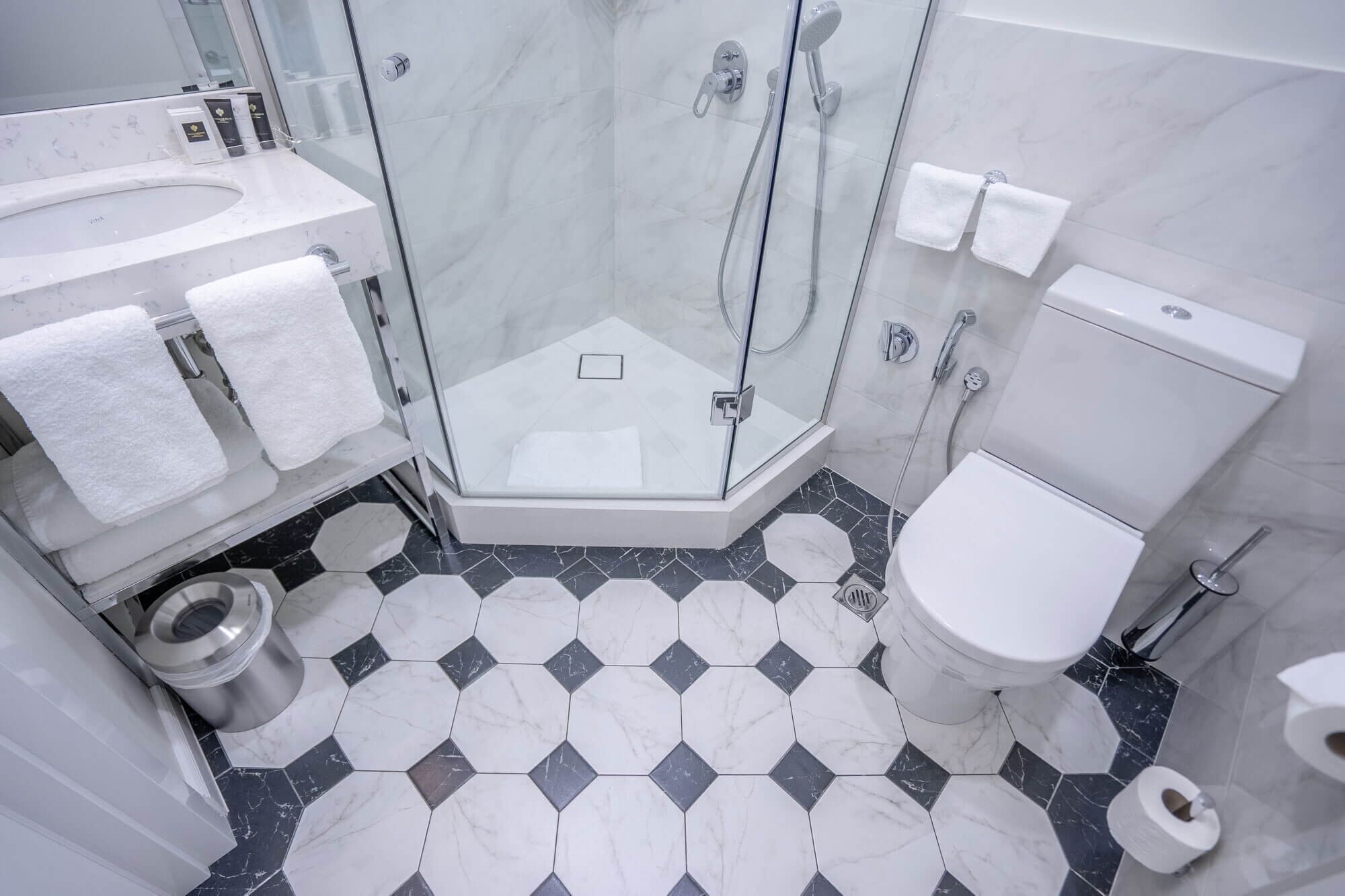 A modern bathroom with a glass-enclosed shower, a white toilet, and a marble-tiled floor.