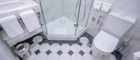 A modern bathroom with a glass-enclosed shower, a white toilet, and a marble-tiled floor.