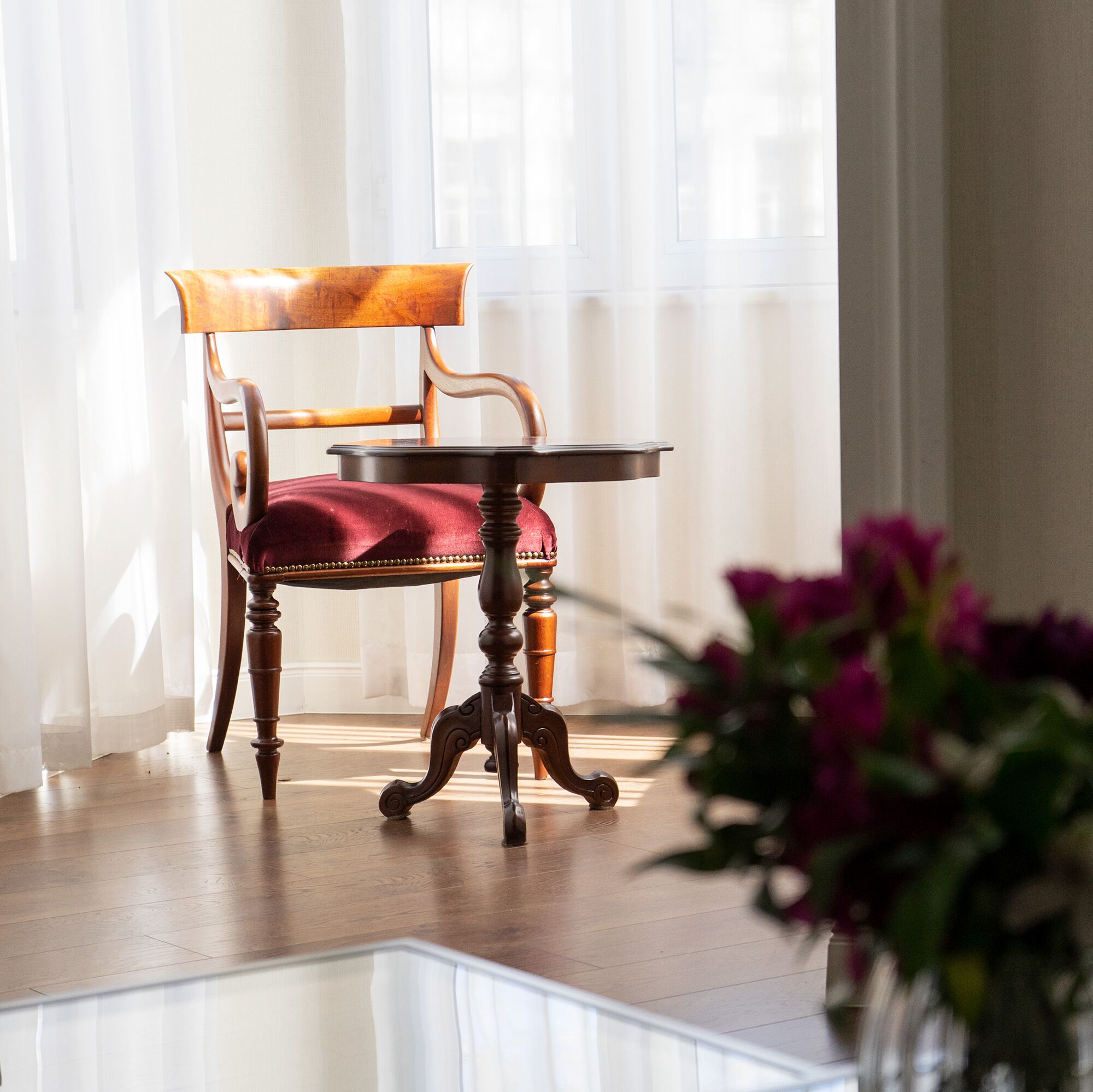 A wooden chair with a red cushion and a small table in front of it.
