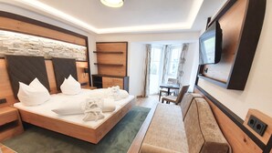 Une chambre d’hôtel moderne dotée d’un grand lit, d’un canapé, d’une télévision et d’un coin repas avec une table et des chaises.