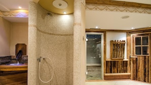 Une salle de bain avec une douche aux murs recouverts de mosaïques, des éléments décoratifs en bois et une porte visible donnant sur une autre pièce.