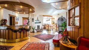 Un hall d’hôtel avec un comptoir d’accueil incurvé, une cheminée et un sapin de Noël.