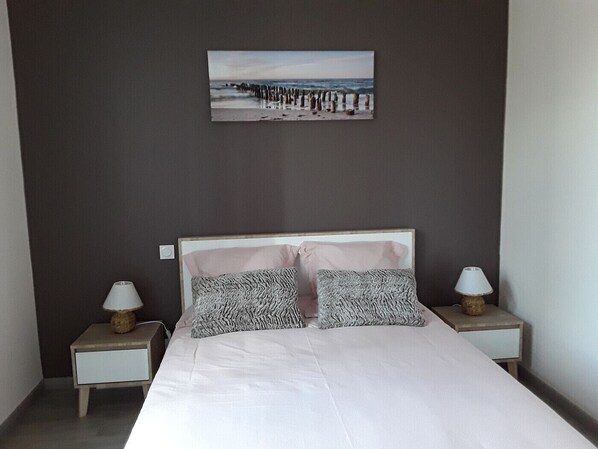 Quarto com uma cama, duas mesas de cabeceira e um quadro na parede.