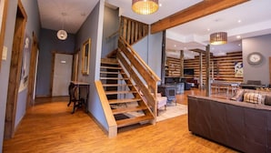 Ein geräumiger Wohnbereich mit einer Holztreppe, einem Kamin und einem großen Sofa.