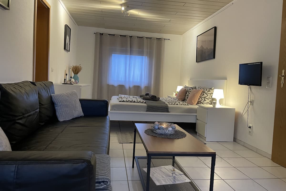 A modern living room with a sofa, a coffee table, and a TV mounted on the wall.
