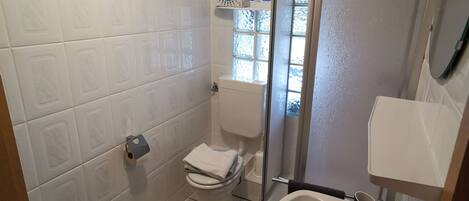 A bathroom with a toilet, sink, and shower.