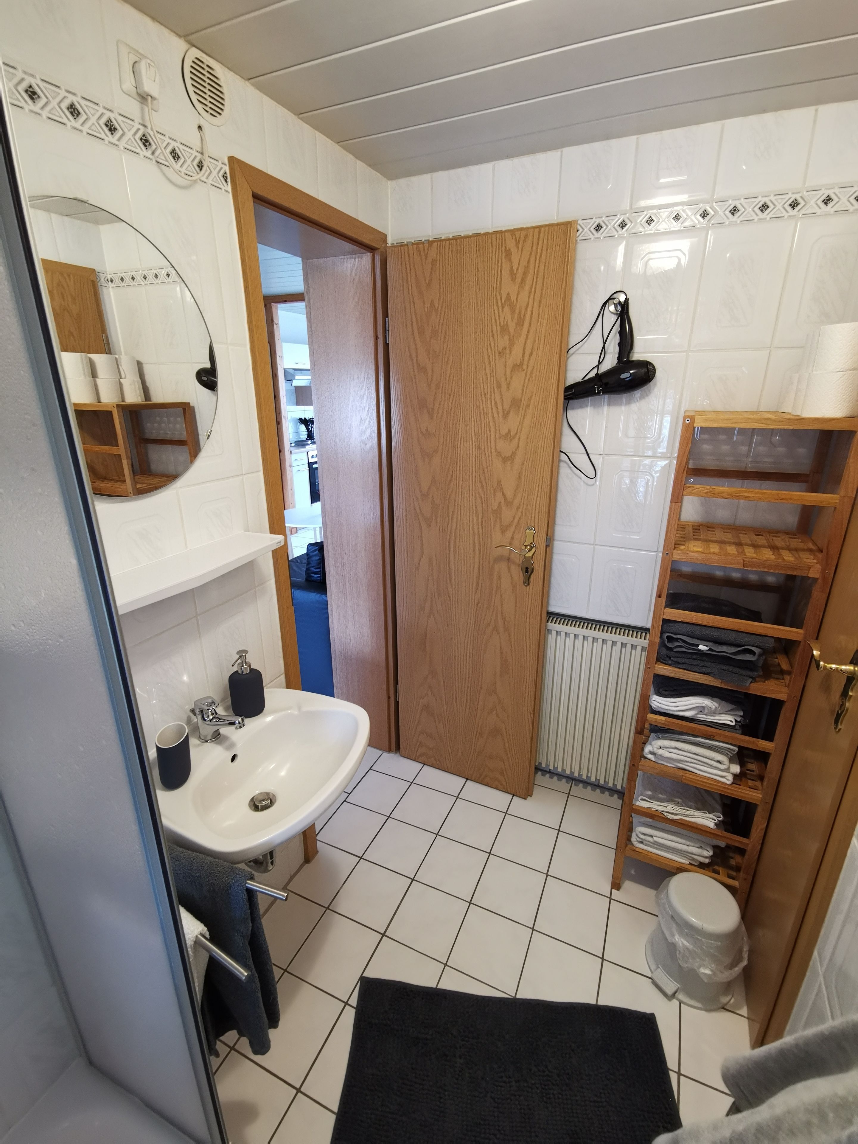 A bathroom with a white sink, mirror, and wooden door.