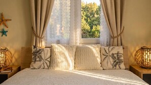 A bedroom with a bed, two nightstands, a window with curtains, and wall decorations.
