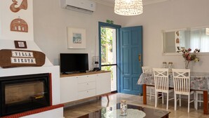 A living room with a TV, fireplace, dining table with chairs, and a blue door.