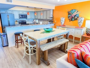 A modern kitchen with a central island, bar stools, and a dining table with benches.