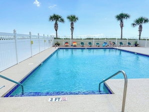 A rectangular swimming pool with a white fence and palm trees in the background. - Beach Club I 3E (North Myrtle Beach)