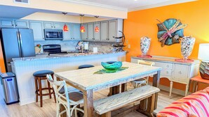 Une cuisine avec un îlot central, des chaises en bois, une table à manger et un canapé coloré.