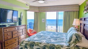 Une chambre à coucher avec un lit, une commode, un téléviseur et une vue sur l’océan.