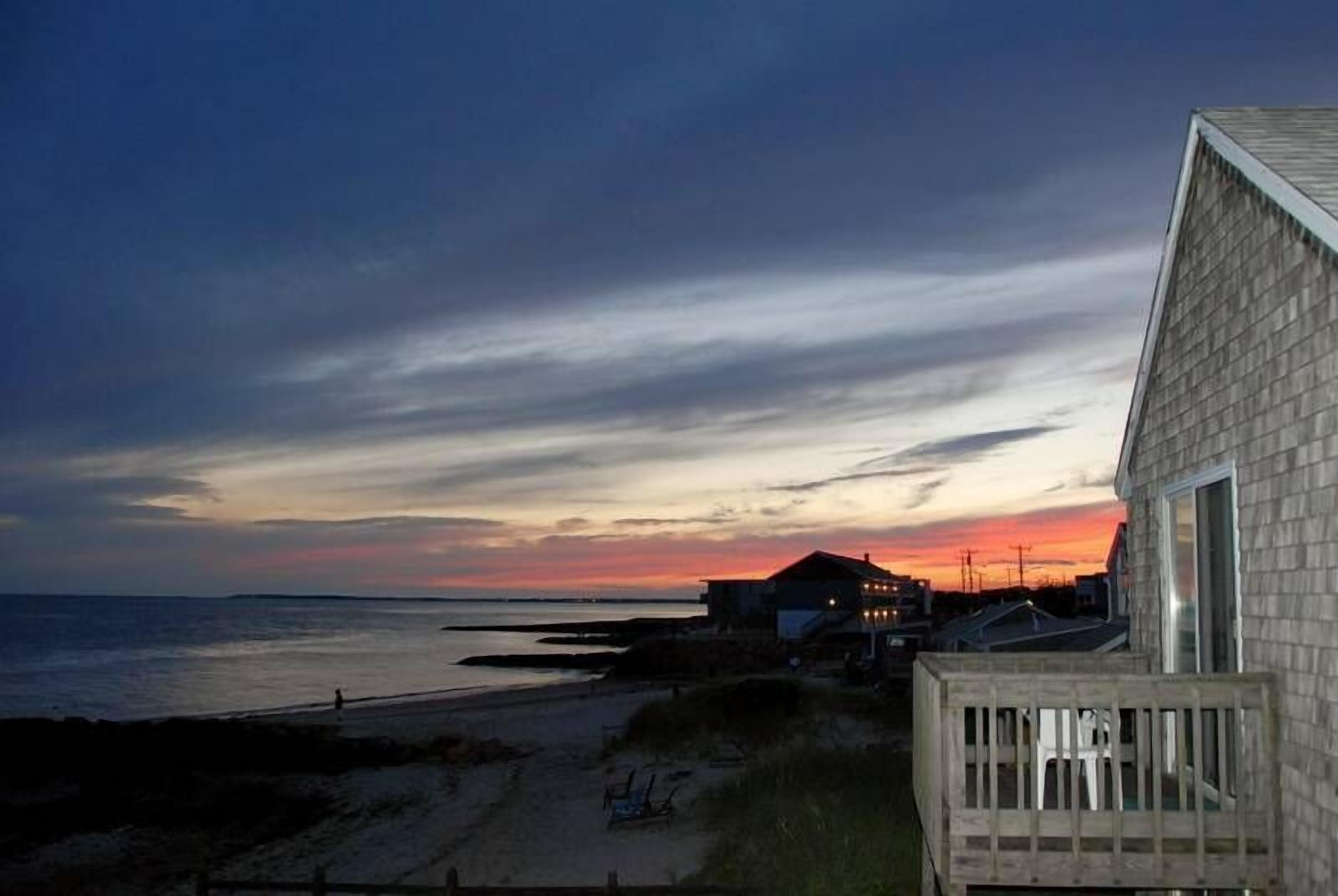 A beach view with a house and a wooden deck.