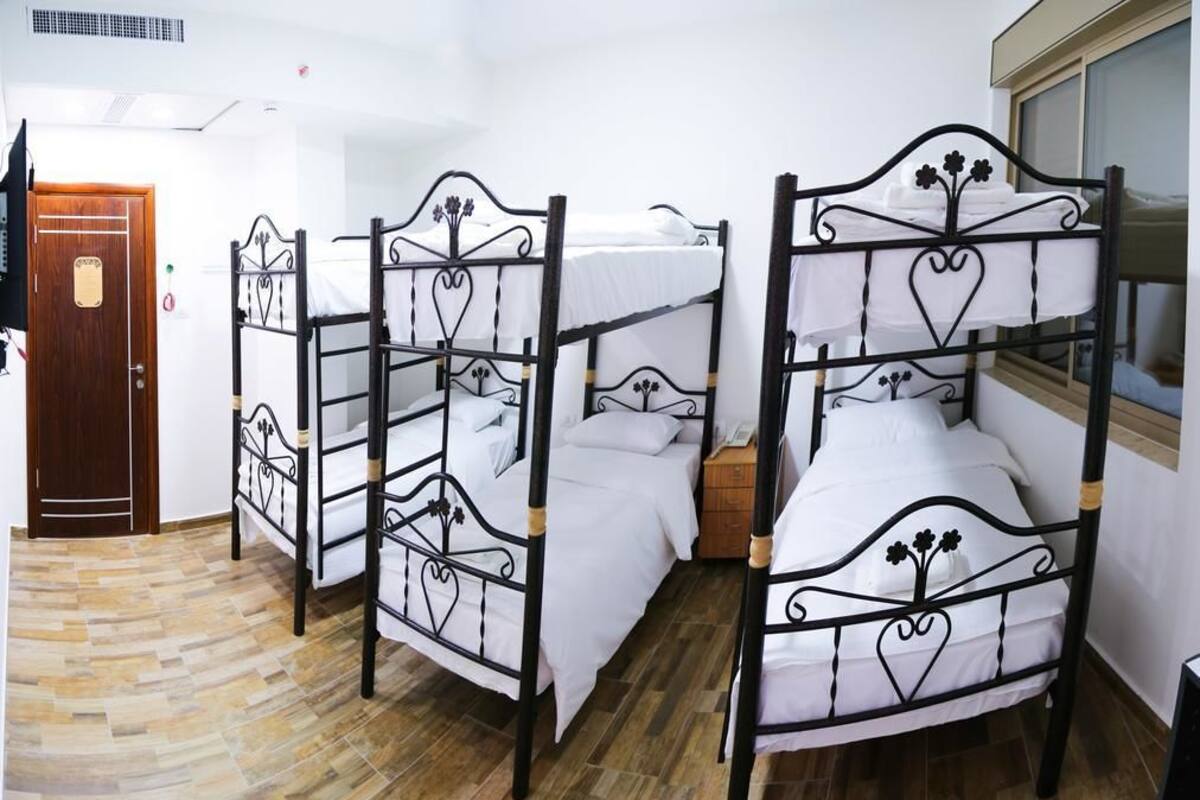 A room with three bunk beds, a wooden door, and a window.