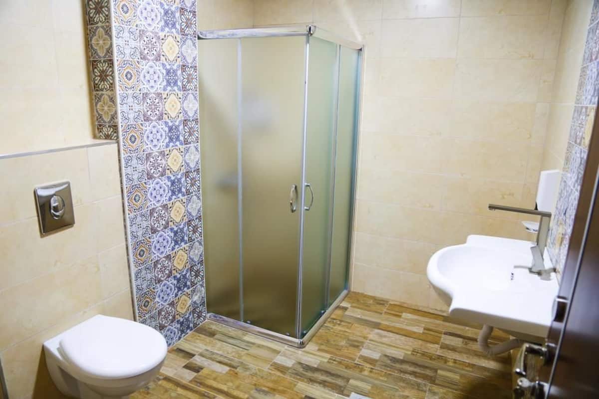 A bathroom with a toilet, a shower with a glass door, and a sink.