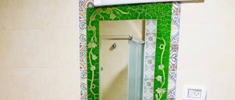 A bathroom with a white sink, a mirror, and patterned tiles on the walls and floor.