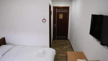Une chambre d’hôtel avec un lit, une table en bois, une chaise, un téléviseur et une porte avec une plaque.