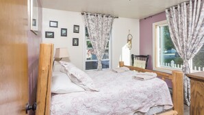 Un letto di legno con copriletto floreale, un comodino, una lampada e una finestra con tende.