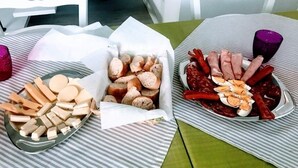 A table with two plates of food, one with bread and cheese, and the other with various meats and sausages.