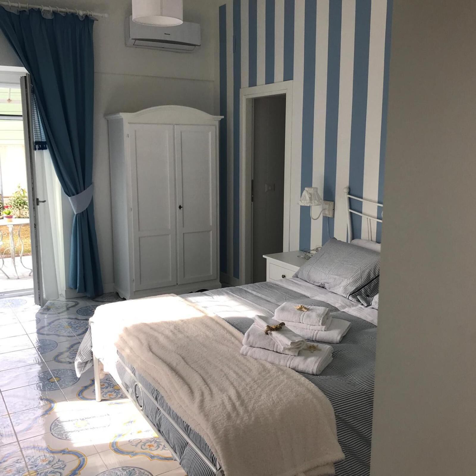 Un dormitorio con cama, armario, mesita de noche y puerta al baño.