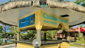 A yellow structure labeled "Cabiloa Sunset Beach Resort" with a mural of a turtle and shark. - Cabilao Sunset Dive & Beach Resort (Loon)