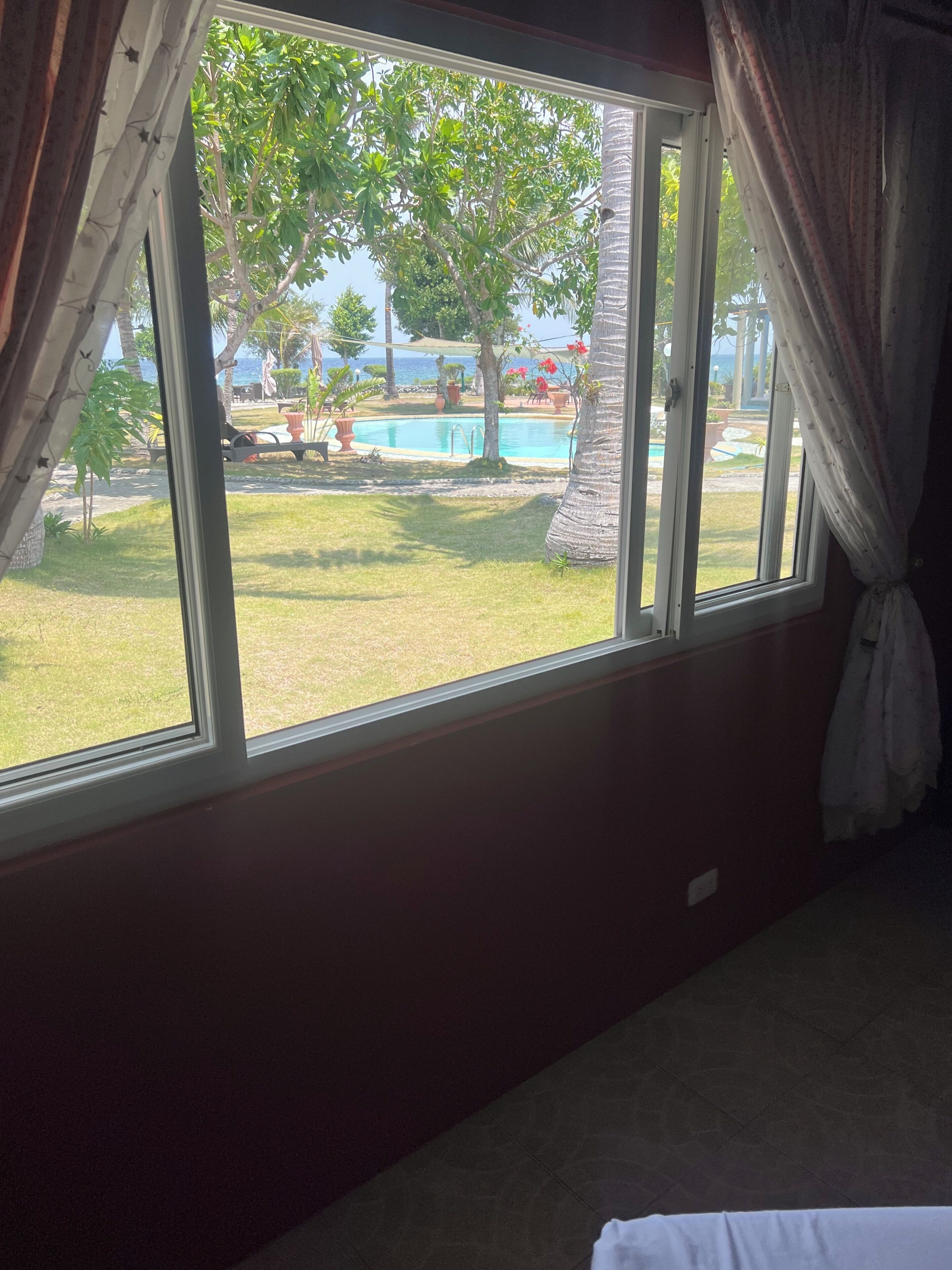 A room with a large window overlooking a pool and a grassy area with trees.