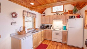 A compact kitchen with wooden cabinets, a white stove, and a refrigerator. - Cozy 3BR Cabin w/ Long-Range Views, Hot Tub & Dog-Friendly (Todd)