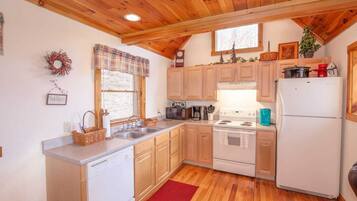 Une cuisine de taille réduite, avec des meubles de rangement en bois, une cuisinière blanche et un réfrigérateur.