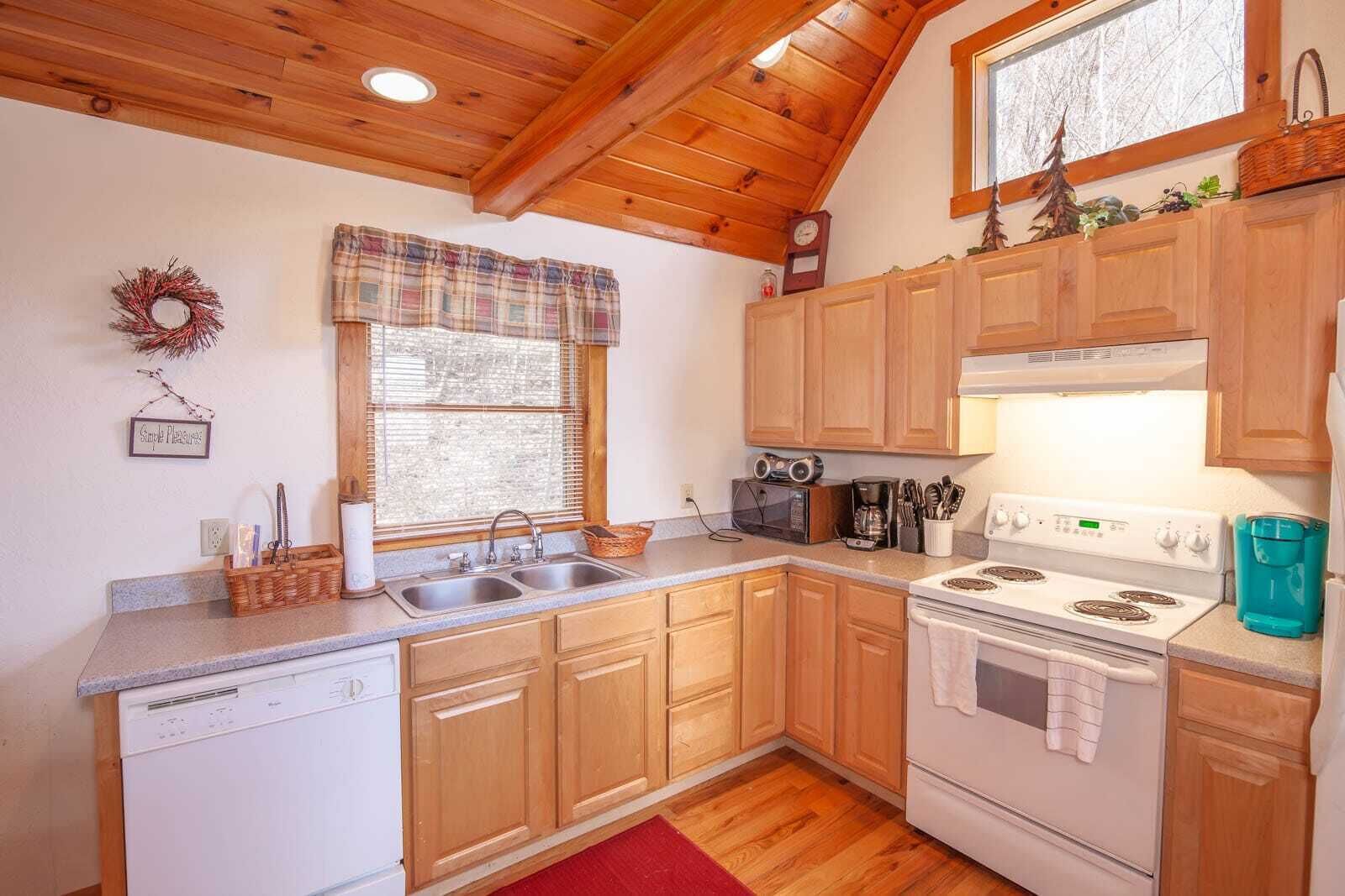 A compact kitchen with wooden cabinets, a white stove, and a microwave.