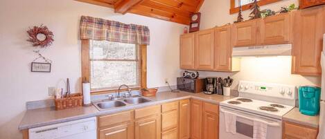 A compact kitchen with wooden cabinets, a white stove, and a microwave.