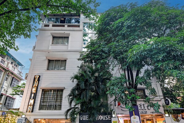 Un edificio de varios pisos con un letrero que indica 'GUEST HOUSE', señal de alojamiento para huéspedes.