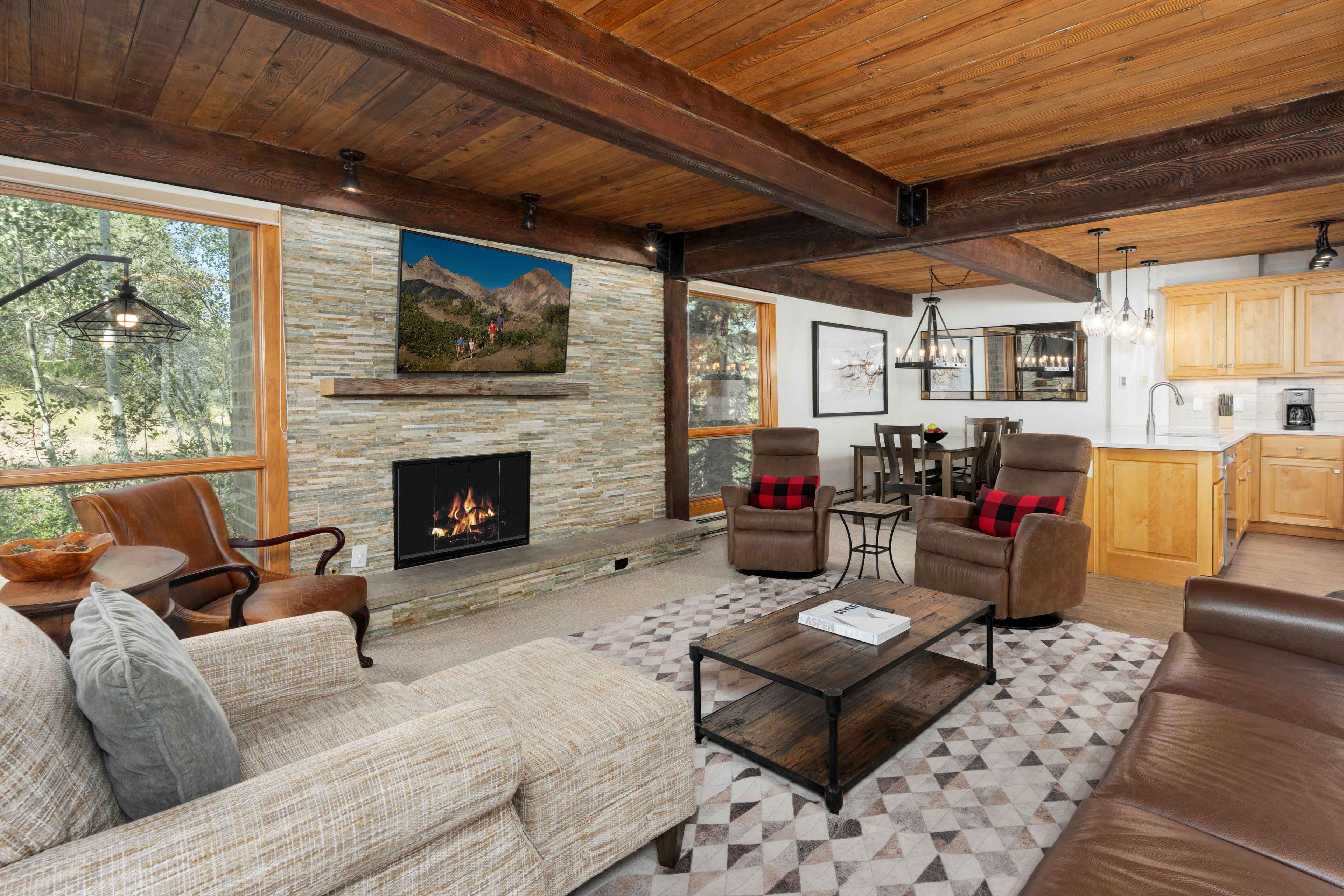A spacious living room with a fireplace, leather sofas, and a dining area with wooden cabinets.