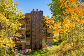 Un edificio de varios pisos con chimenea de ladrillo, balcones y un jardín bien cuidado.